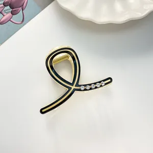 Détail de la pince à cheveux dorée avec émail noir et cinq strass brillants