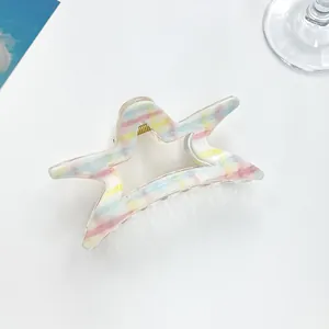 Dettaglio macro della molletta a stella con strisce pastello e molla dorata