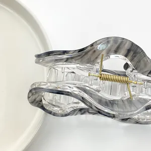 Detalle de pinza para el pelo de nube translúcida con patrón de mármol gris y resorte dorado