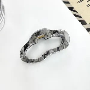 Primer plano de pinza de resina veteada con resistente resorte de metal dorado