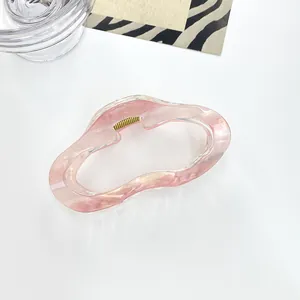 Detalle de pinza para el pelo jaspeada rosa y blanca con diseño de onda hueca