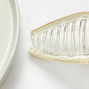 Elegant translucent acrylic shark hair claw with gold rim and minimalist stone texture design
