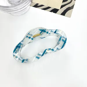 Detalle de pinza para el pelo a cuadros azules y blancos con muelle de metal dorado