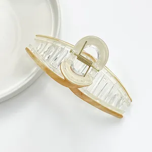 Detail of amber marble texture acrylic hair claw clip with golden metal spring