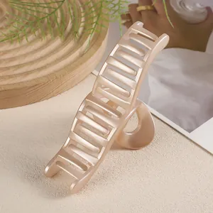Détail d'une grande pince à cheveux rose champagne posée sur un plateau en bois