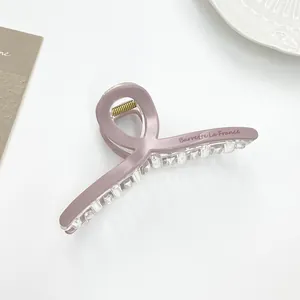 Macro detail of matte pink hair claw clip with golden spring and brand lettering