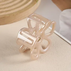 Détail d'une pince à cheveux fleur en plastique rose nacré avec pétales ajourés