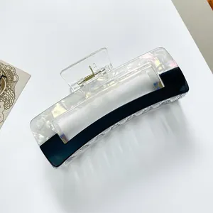 Detail showing the rectangular geometric hair claw clip with pearlescent shell texture