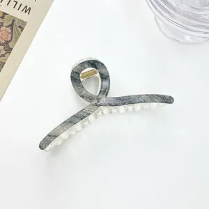 Macro detail of high-quality marble pattern hair claw clip with golden metal spring