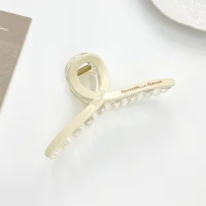 Detail of a large cream claw clip featuring Barrette La France text and a metal spring
