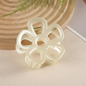 Macro d'une pince à cheveux fleur crème sur un plateau en bois avec des feuilles