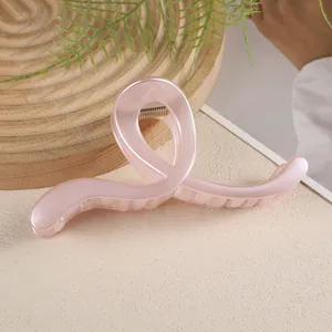 Détail macro d'une pince à cheveux géométrique de 13cm rose clair translucide sur un plateau