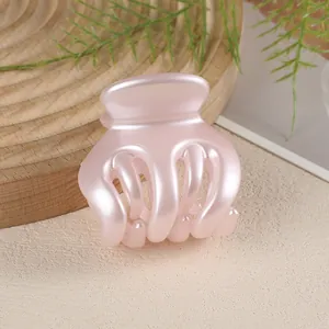 Close-up of a pearlescent pink pumpkin claw clip on a natural wooden display stand