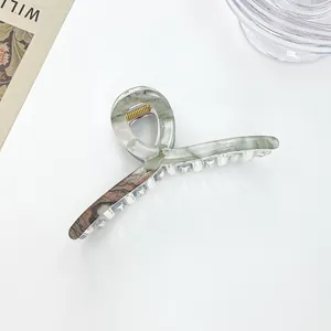 Detail of large marble texture hair claw with premium gold spring on white background