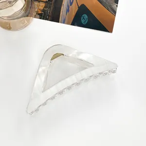 Close-up of a cream triangle hollow hair claw clip with golden metal spring