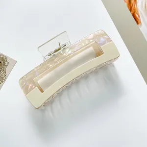 Detail of a rectangular hair claw clip in pearlescent pink and cream white acetate