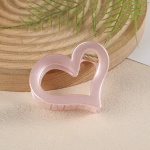 Vue détaillée d'une pince à cheveux cœur évidé rose perle avec ressort doré