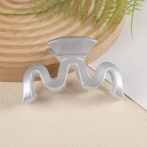 Détail d'une pince à cheveux ondulée en M avec finition blanc nacré sur bois