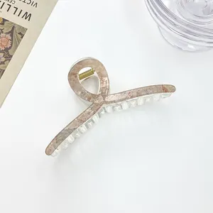 Macro shot of large brown marble pattern hair claw clip with golden metal spring