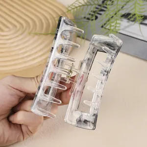 Medium ink marble resin hair claw clip for elegant updo hairstyles in a handheld shot