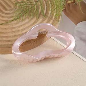 Détail de la pince à cheveux nuage rose nacré de 11cm sur un plateau en bois