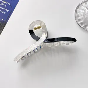 Detail of a large black and white marble hair claw clip with a gold metal spring