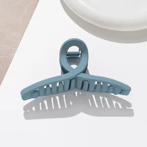 Détail de pince à cheveux bleu mat montrant le ressort en métal et le design croisé