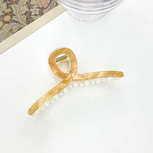Top view of large amber marble pattern hair claw clip on white surface with decor