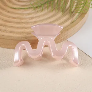 Détail d'une pince à cheveux ondulée en M au fini rose perle brillant translucide