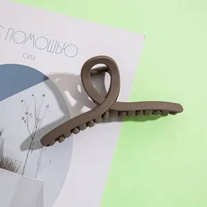 Détail d'une grande pince à cheveux marron mat avec un design torsadé en résine