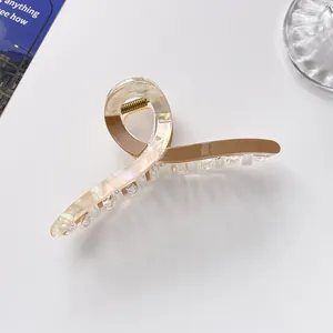 Detail of a large pearlescent and brown acrylic hair claw clip with strong gold metal spring