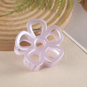 Détail d'une pince à cheveux en forme de fleur évidée rose clair avec ressort en métal