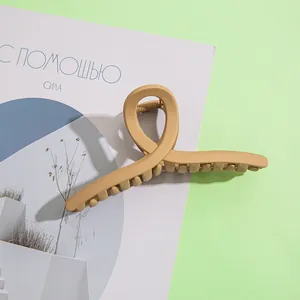 Détail macro d'une grande pince à cheveux mate kaki avec un design croisé torsadé sur papier