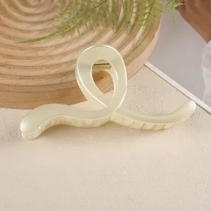 Détail d'une grande pince à cheveux crème au design géométrique torsadé en résine