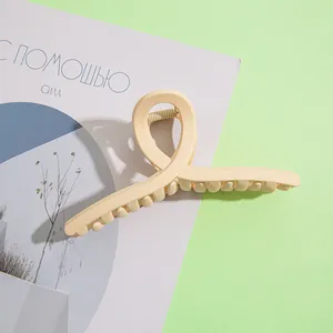 Vue détaillée d'une grande pince à cheveux mate crème avec design croisé et torsadé