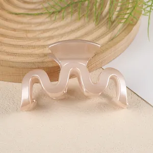 Détail macro d'une pince à cheveux ondulée couleur pêche sur surface texturée