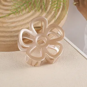 Détail d'une pince à cheveux fleur champagne avec ressort doré sur surface texturée