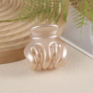 Macro detail of elegant pearlescent champagne pink hair claw clip on wooden base