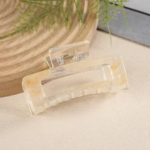 Detail of a medium rectangular hair claw clip with cream marble texture on a wooden tray