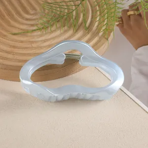 Détail d'une pince à cheveux nuage de 11cm, bleu nacré sur une surface beige