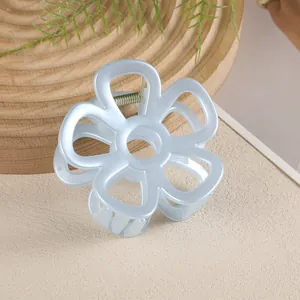 Vue détaillée de la pince à cheveux fleur évidée bleu clair sur un plateau en bois