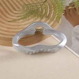 Détail d'une pince à cheveux de 11cm gris argenté ondulée avec finition perle élégante