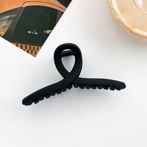 Détail de la pince à cheveux noire mate avec design croisé et dents antidérapantes