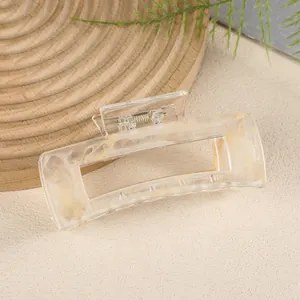 Detailed view of rectangle hair claw clip with ink marble texture on a wooden stand