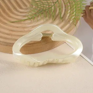 Gros plan sur la pince à cheveux nuage crème de 11cm avec ressort doré sur bois