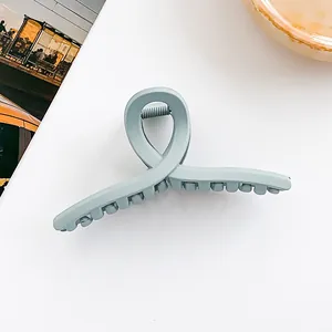 Gros plan d'une pince à cheveux mate bleu clair en résine au design croisé sur fond blanc