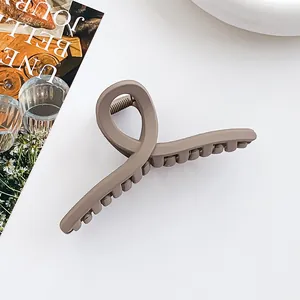 Vue détaillée de la pince à cheveux en résine mate marron avec design croisé et prise ferme