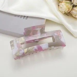Pince à cheveux rectangulaire en marbre rose sur tissu en soie et livre