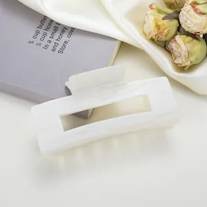Dettaglio della pinza per capelli quadrata in acetato con trama in marmo bianco e design cavo