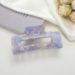 Détail d'une pince à cheveux rectangulaire en acétate marbré sur fond de soie douce
